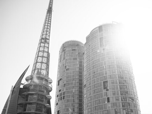Modern architecture in sunlight – a high-contrast black and white image of curved glass buildings and a steel tower.